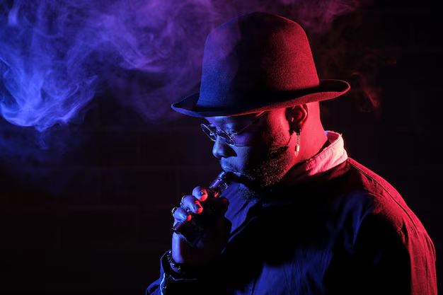 imgi_93_side-view-bearded-man-hat-smoking-vape-while-standing-with-sunglasses-dark-room_935394-7379